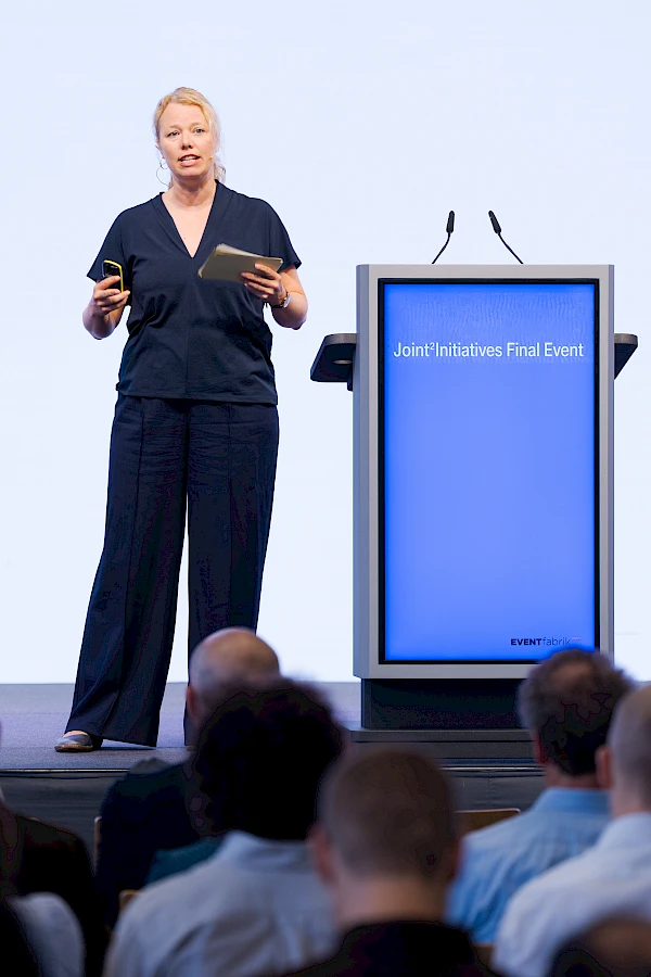ventfotograf Bern für Firmenanlässe – Professionelle Fotografie einer Referentin beim Joint Initiatives Final Event in der Eventfabrik Bern. Diskrete, hochwertige Eventfotografie, die die Dynamik und Professionalität deiner Business-Veranstaltung einfängt."